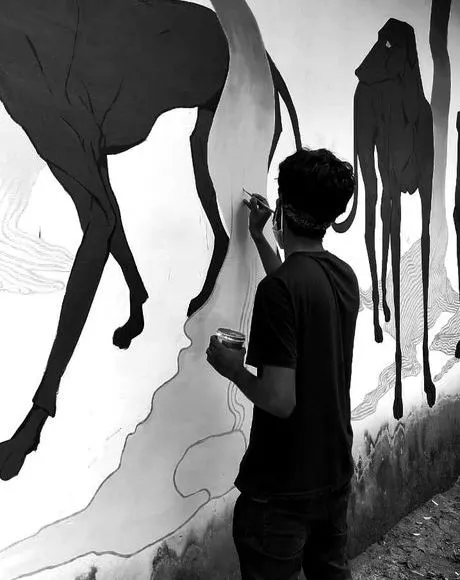 Akhil painting a black and white mural of animals