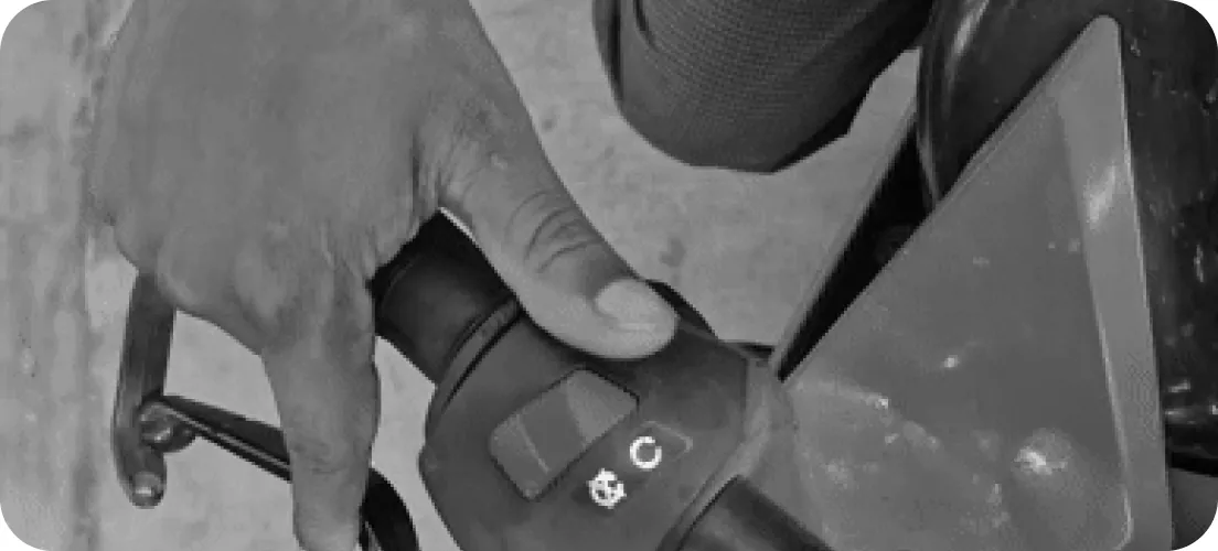 A thumb reaching for the switch cluster on a motorbike’s left grip