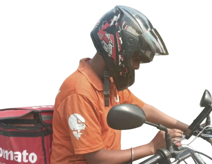 A delivery rider in a helmet and an orange Zomato T-shirt, leaning over the handlebar of his bike
