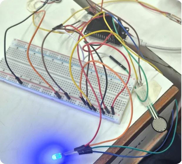 A breadboard with an ESP32, jumper wires, a force sensor and a blue LED lit